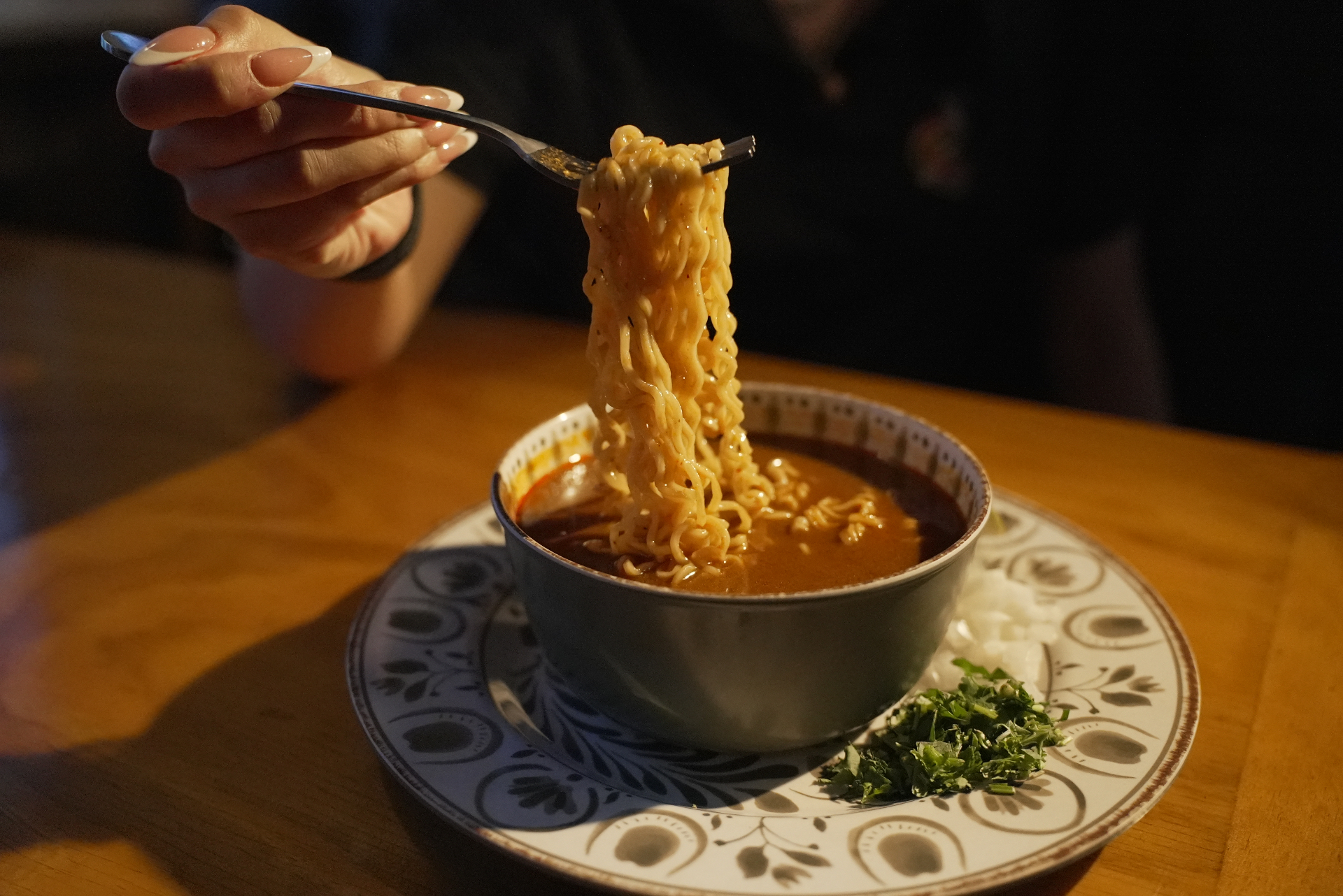 Birria ramen being lifted from the bowl at Chela's