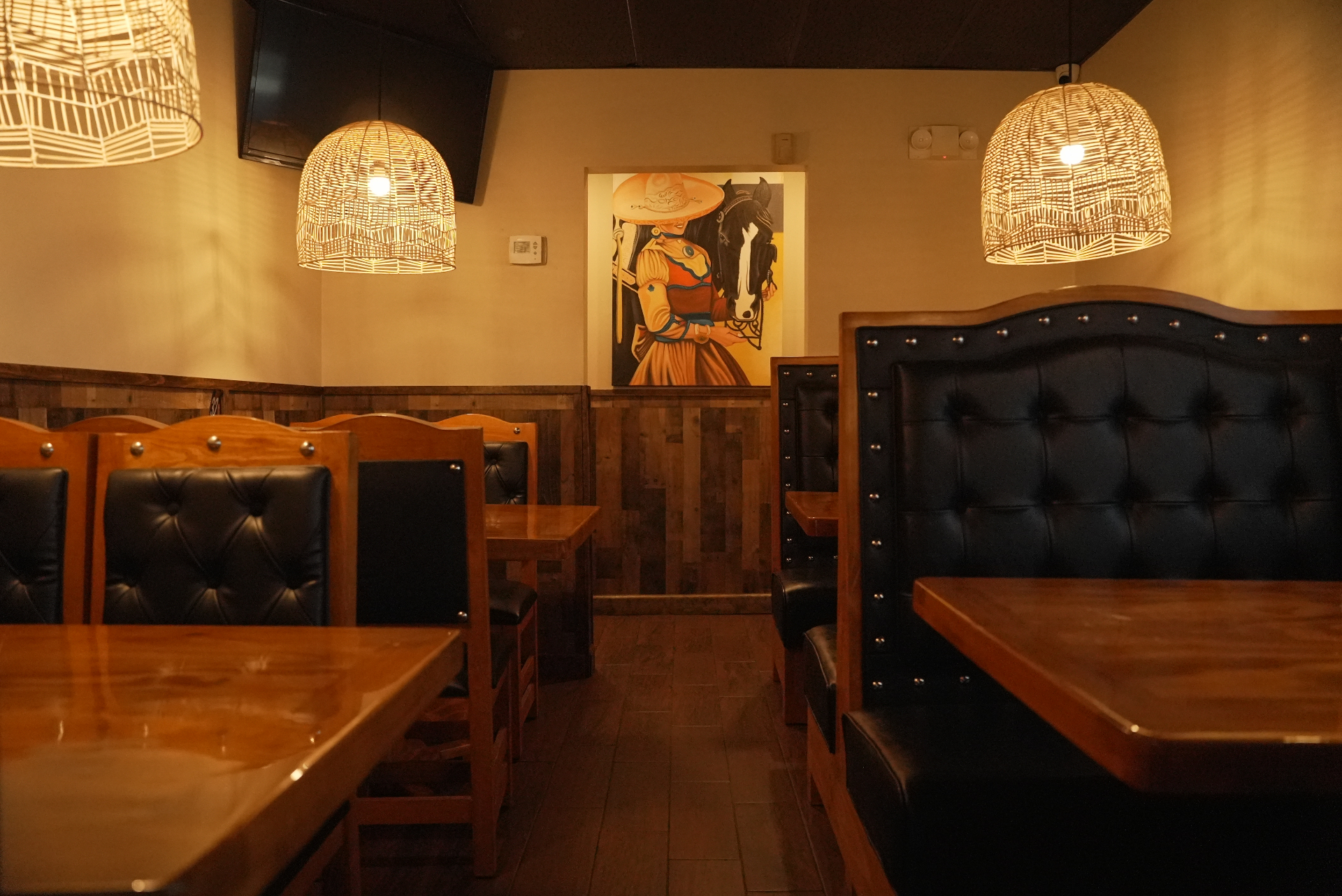 Warm dining room inside Chela's Birria Tacos with wood booths and hanging lights